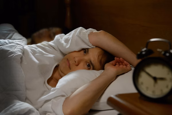 Woman awake in bed alarm clock next to bed