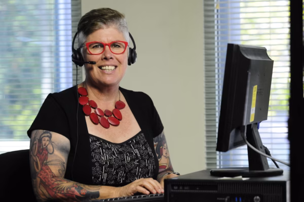 Epilepsy support worker with headphones working at computer